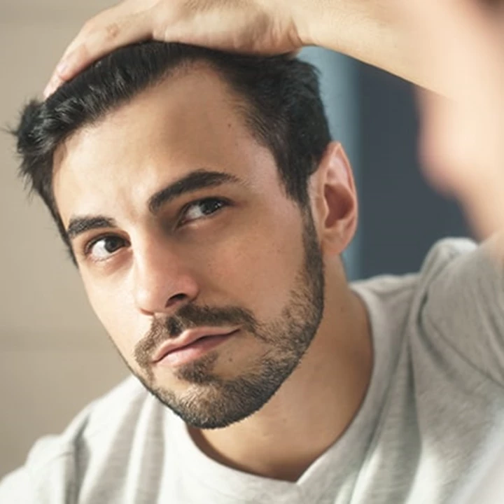 Mann vor dem Spiegel Mann fragt sich was hilft gegen Schuppen