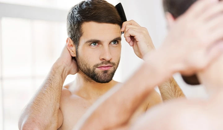 Mann kämmt seine Haare Ein seborrhoisches Ekzem betrifft vor allem den Kopf