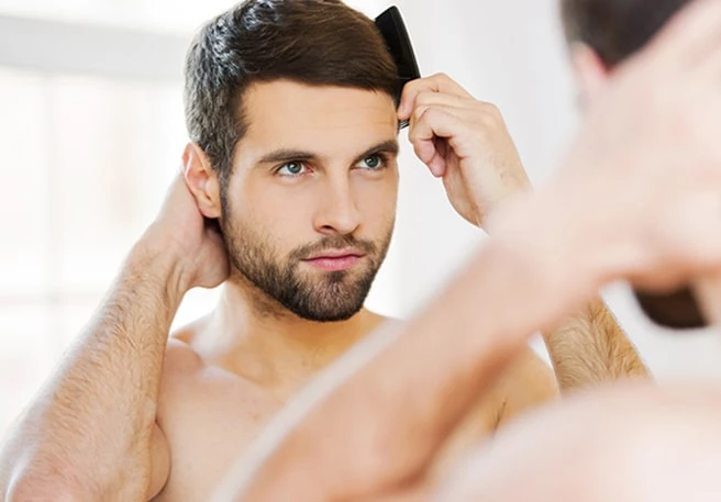 Mann kämmt seine Haare Ein seborrhoisches Ekzem betrifft vor allem den Kopf